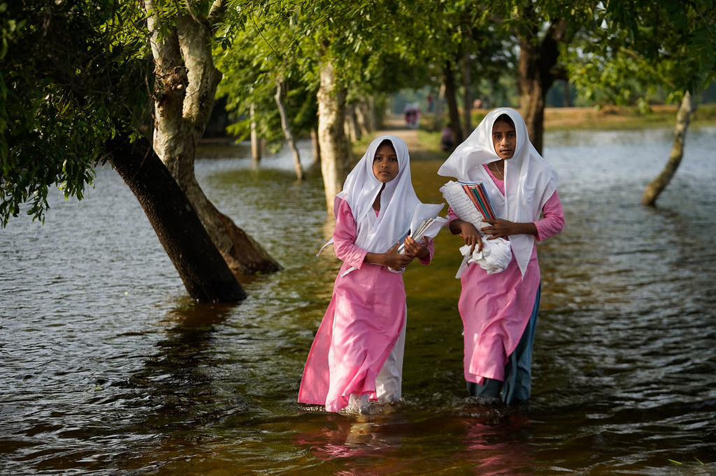 Girls wade through floodwaters on their way to school in Sunamganj, Bangladesh.