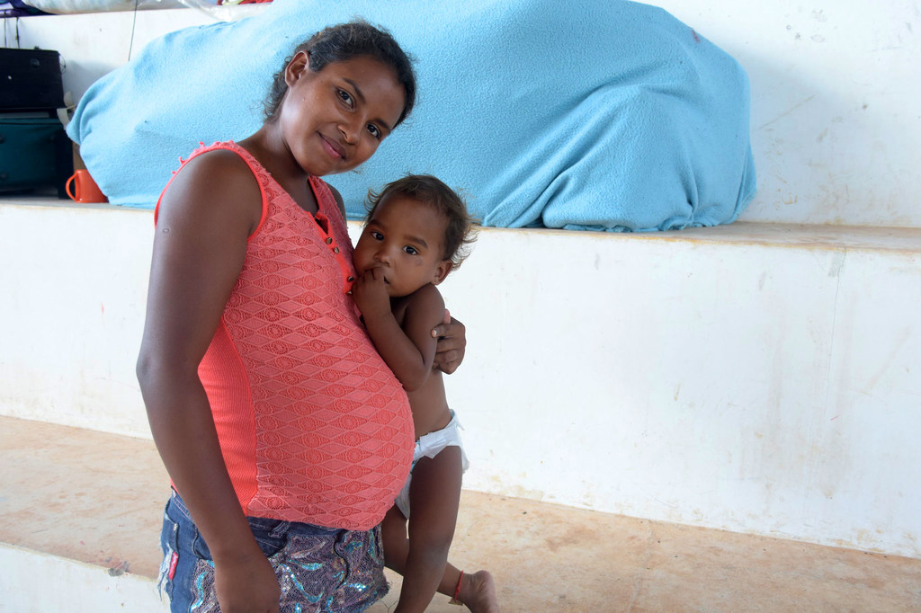 A pregnant Brazilian woman carries her daughter.