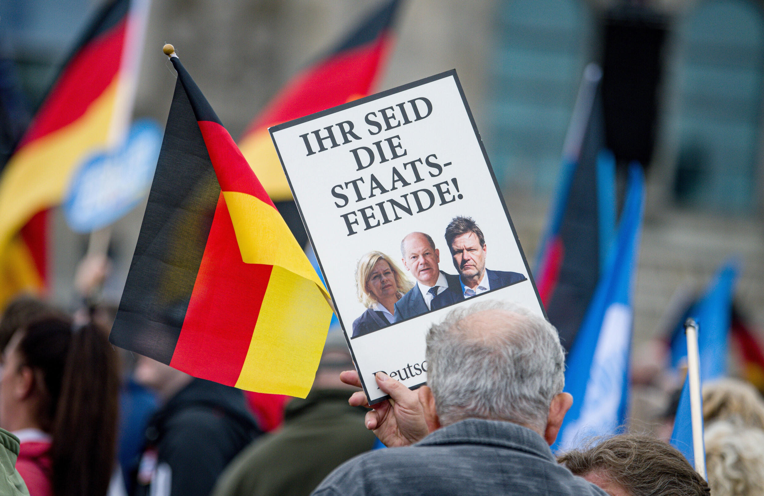 A man sympathizing with the AfD shows a sign during a demonstration on energy security and inflation that reads "They are enemies of the state!" and photos of various members of the Government, including Chancellor Olaf Scholz, in Berlin, on Saturday, October 8, 2022.