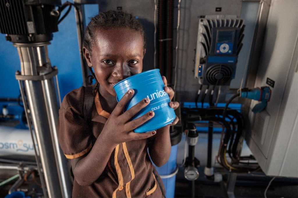 A schoolgirl enjoys drinking water from a UNICEF-supported desalination system.