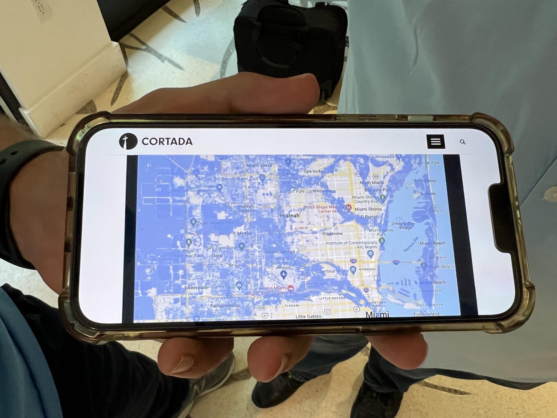 Adam Roberti shows the website of the Cortada Foundation on his cell phone, which shows the map of future sea level rise in Miami.