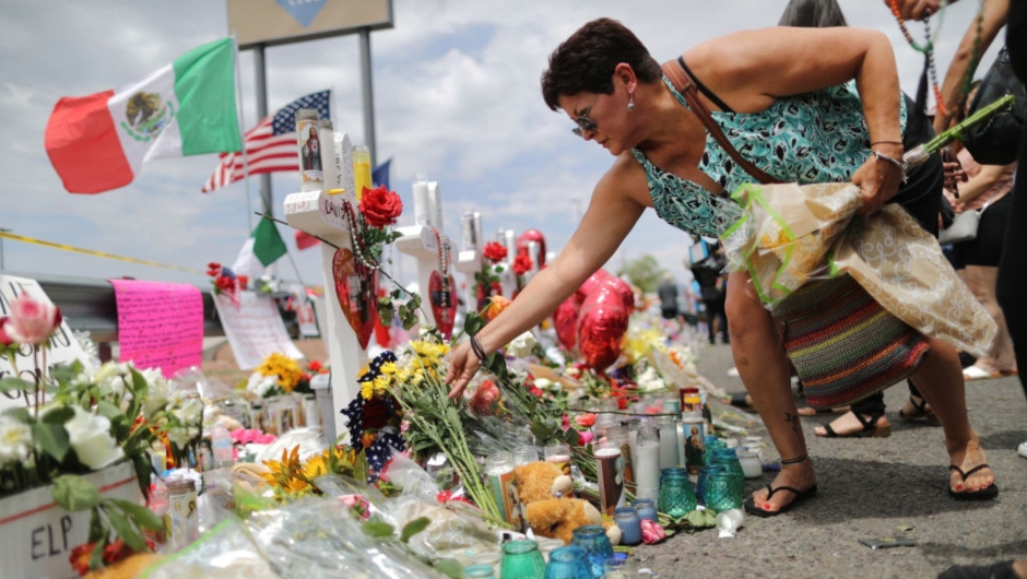 A woman places flowers while waving Mexican and American flags at an impromptu tribute to the victims outside a Walmart, near the scene of a mass shooting that left 23 dead, on August 6, 2019 in El Paso, Texas.  (Photo: Mario Tama/Getty Images)