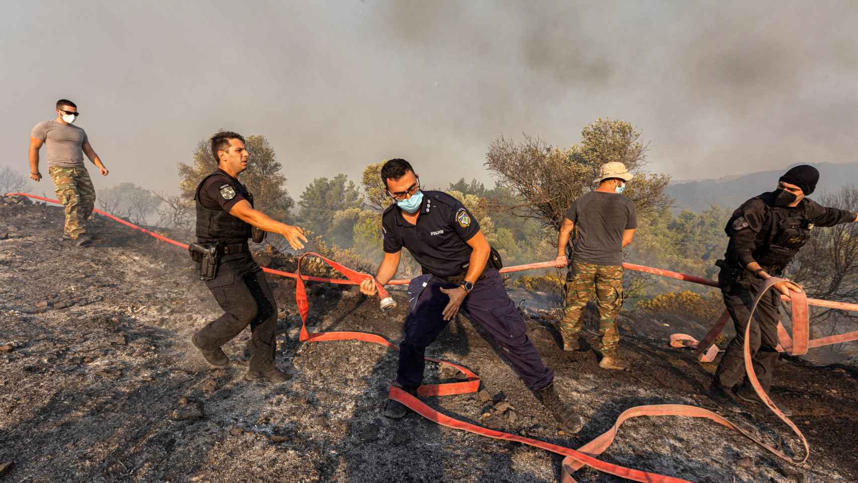 Firefighters, volunteers and police operate as a forest fire burns near the village of Asklipieio, on the island of Rhodes, Greece.  ,