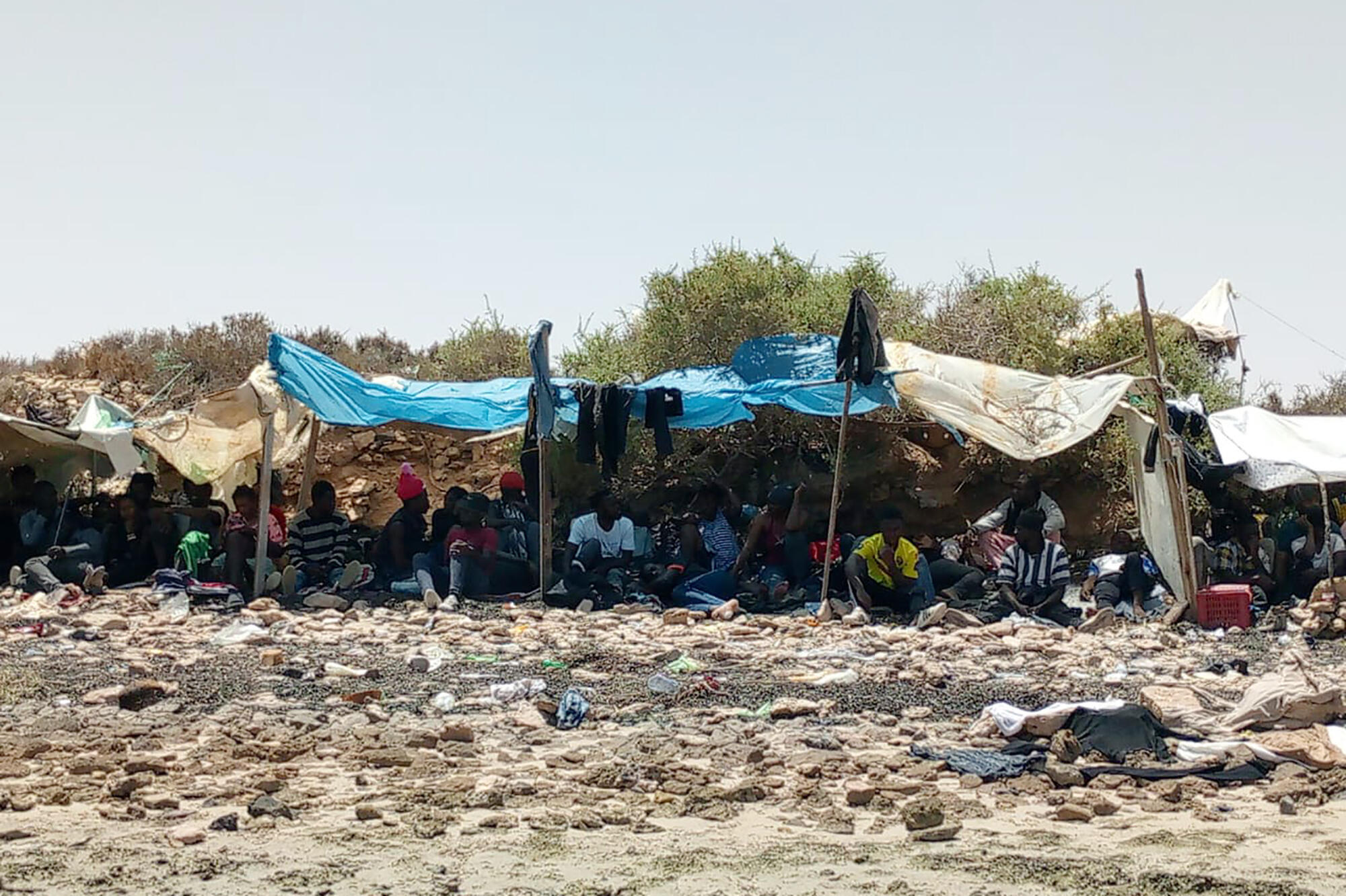 In this photo taken by a migrant from the Ivory Coast, a group of sub-Saharan Africans are seen stranded on a beach believed to be located on the Tunisian-Libyan border, on Thursday, July 6, 2023.