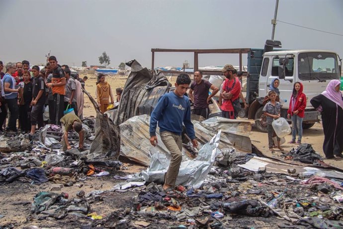 Palestinians in the remains of a fire caused by an Israeli bombardment against a displaced persons camp in Rafah, in the southern Gaza Strip