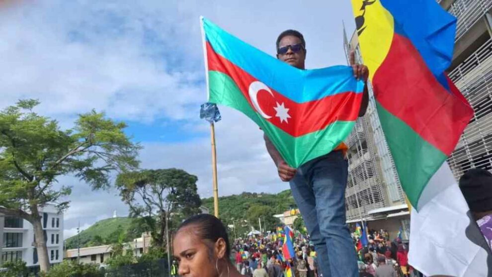 A protester waves the Azerbaijani flag next to a Kanak flag on May 16 in Noumea.