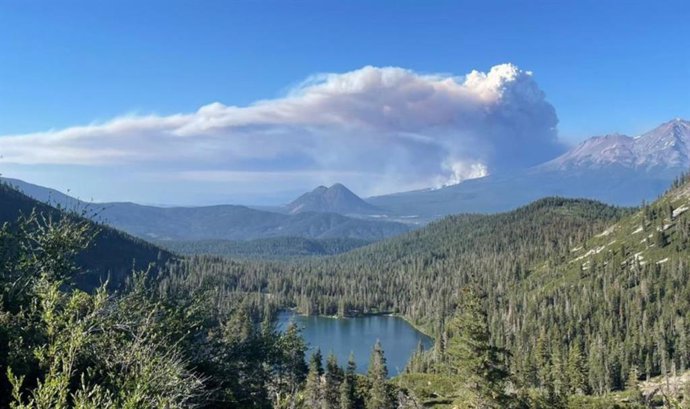 A plume of smoke from a wildfire rises over Castle Lake near Mount Shasta on June 29, 2021.