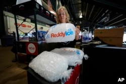 Cheryl Batch picks up a bag of ice to use for cool beverages at a stand on the main concourse of Coors Field before the Colorado Rockies host the Pittsburgh Pirates in a baseball game Sunday, June 16, 2024, in Denver.  (AP Photo/David Zalubowski)