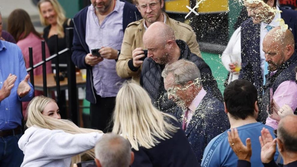 A young woman throws a milkshake in the face of populist Nigel Farag