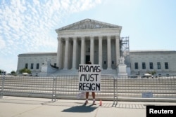 A woman holds a sign calling for the resignation of U.S. Supreme Court Justice Clarence Thomas outside the Supreme Court, before the ruling was issued in Washington, United States, June 14, 2024. REUTERS/Elizabeth Frantz