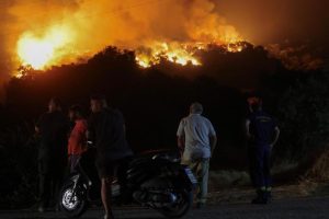 Locals observe a forest fire in the town of Latas (Greece).