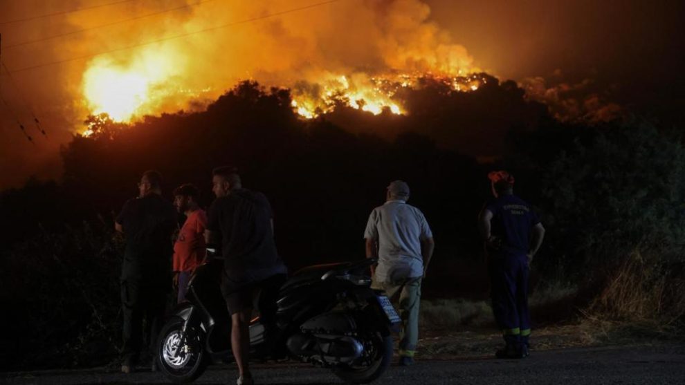 Locals observe a forest fire in the town of Latas (Greece).