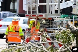 A worker clears debris from the streets of Houston, Wednesday, July 10, 2024, after Hurricane Beryl hit Texas and knocked out power to nearly 3 million homes and businesses.