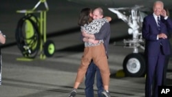 Reporter Evan Gershkovich hugs his mother, Ella Milman, as President Joe Biden looks on at Andrews Air Force Base, Maryland, following his release as part of a prisoner exchange between Russia and the United States, Aug. 1, 2024.