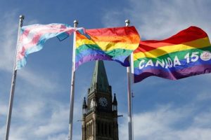 Transgender pride flags, left, gay pride flag, center, and the 150 Years of Canada Pride flag wave after a flag ceremony on Parliament Hill in Ottawa, Canada, June 14, 2017.