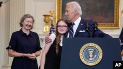 President Joe Biden hugs Miriam Butorin, the infant daughter of freed journalist Alsu Kumarsheva, as Elizabeth Whelan, left, looks on after delivering remarks on a prisoner swap with Russia, at the White House, Aug. 1, 2024.