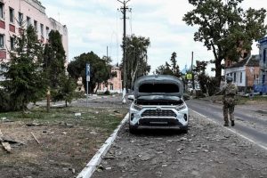 A Ukrainian soldier patrols in front of buildings damaged by the attacks in Sudzha.