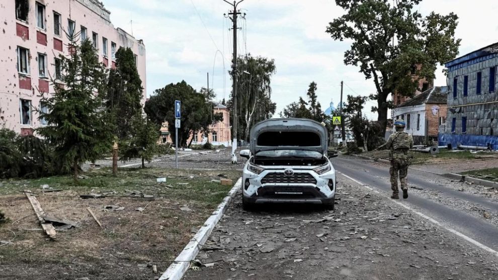 A Ukrainian soldier patrols in front of buildings damaged by the attacks in Sudzha.