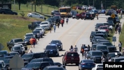 People walk past cars parked on the sides of a road near the scene of the shooting at Apalachee High School in Winder, Georgia, U.S., September 4, 2024.