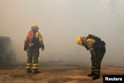 Firefighters rest as they work to extinguish a forest fire, in Quito, Ecuador, September 24, 2024. REUTERS/Karen Toro