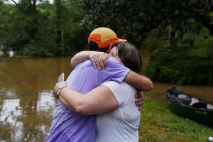 Dan Murphy hugs his colleague after taking his canoe to rescue them from their flooded home, as the streets are flooded near Peachtree Creek, on September 27, 2024 in Atlanta, Georgia.