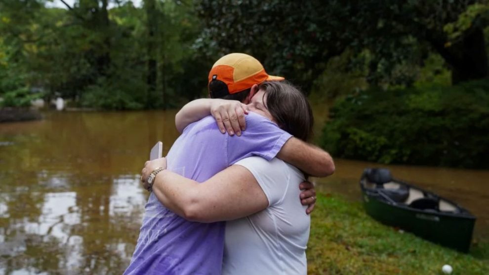 Dan Murphy hugs his colleague after taking his canoe to rescue them from their flooded home, as the streets are flooded near Peachtree Creek, on September 27, 2024 in Atlanta, Georgia.