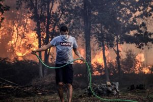 A man holds a hose while fighting a forest fire in Macinhata da Seixa, Oliveira de Azemeis.