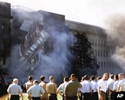 FILE - Military and Pentagon personnel look at the area where the commercial airliner crashed into one side of the Defense Department headquarters on Tuesday, Sept. 11, 2001.