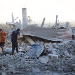 Palestinians inspect the remains of a building destroyed by Israeli attacks