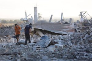 Palestinians inspect the remains of a building destroyed by Israeli attacks