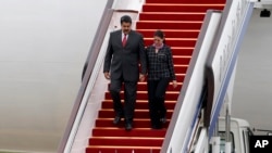 FILE - Venezuelan President Nicolas Maduro and first lady Cilia Flores walk down the steps of their plane at Beijing International Airport in Beijing, China, Sept. 1, 2015.