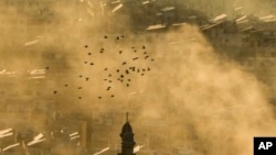 A flock of birds flies as smoke rises from the site of an Israeli airstrike in Dahiyeh, in the southern suburb of Beirut, Lebanon, Thursday, Oct. 24, 2024. (AP Photo/Bilal Hussein)