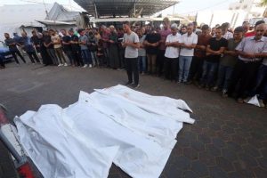 A group of people pray to their dead - victims of Israel's attacks - at the doors of a hospital in Gaza.