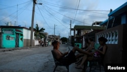 FILE - People sit outside their homes during a power outage caused by breakdowns that forced six plants to disconnect from the grid, according to the state electricity company, in Matanzas, Cuba, August 22, 2024. REUTERS/Norlys Perez.