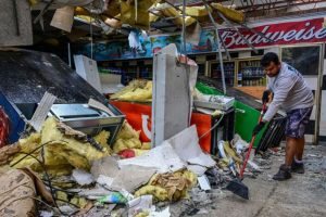 A man clears debris inside a gas station store in Lakewood Park, Florida, after a tornado hit the area as Hurricane Milton moved through the region on October 10, 2024.