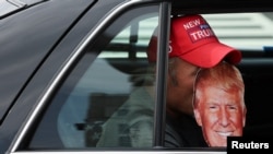 FILE - A person holds a Trump mask inside a vehicle on the day former U.S. President Donald Trump appears in U.S. District Court in Washington, Aug. 3, 2023.