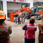 Fire and Rescue Department workers search for a woman who fell into a sinkhole after a section of sidewalk collapsed in Kuala Lumpur on August 23, 2024. Credit: Vincent Thian/AP