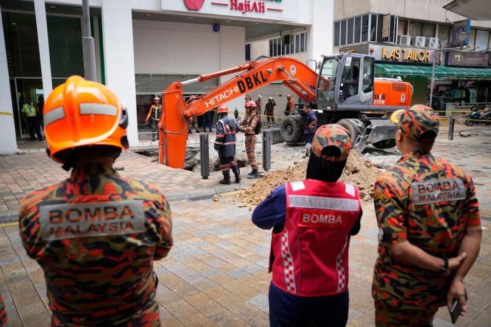 Fire and Rescue Department workers search for a woman who fell into a sinkhole after a section of sidewalk collapsed in Kuala Lumpur on August 23, 2024. Credit: Vincent Thian/AP