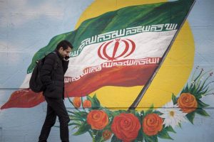 File - February 17, 2020, Tehran, IRAN: Iranians walk next to a wall painting of the Iranian national flag in Tehran, Iran. Many Iranians, battered by economic sanctions, political turmoil and the lingering threat of military conflict, say they are in