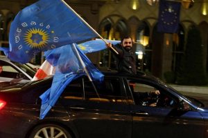 A supporter of the Georgian Dream party waves the party flag from a car after the results were announced.