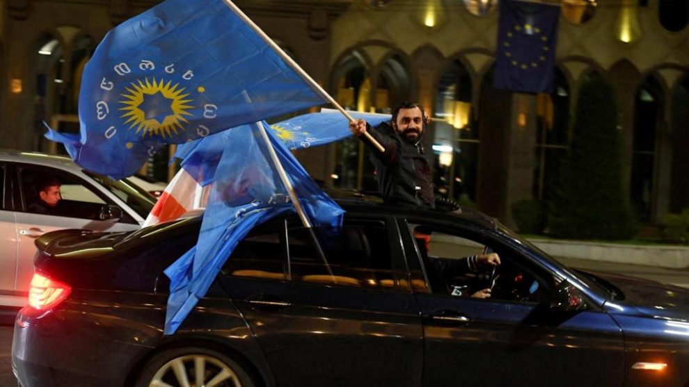 A supporter of the Georgian Dream party waves the party flag from a car after the results were announced.