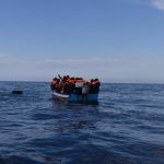 File - Migrants in a wooden boat, who left the coast of Libya, wait to be rescued by members of the NGO Open Arms, on March 5, 2022, off the coast of Libya, in the Mediterranean Sea.