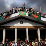 Anti-government protesters display Bangladesh's national flag after storming former Prime Minister Sheikh Hasina's palace in Dhaka on August 5, 2024.