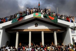 Anti-government protesters display Bangladesh's national flag after storming former Prime Minister Sheikh Hasina's palace in Dhaka on August 5, 2024.