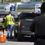 A Florida Highway Patrol trooper watches as workers at a fuel depot distribute gasoline to residents on Saturday, Oct. 12, 2024, in Plant City, Florida. Credit: Chris O'Meara/AP