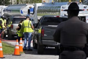 A Florida Highway Patrol trooper watches as workers at a fuel depot distribute gasoline to residents on Saturday, Oct. 12, 2024, in Plant City, Florida. Credit: Chris O'Meara/AP