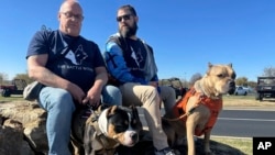 Retired U.S. military personnel Timothy Siebenmorgen, left, and Mark Atkinson, right, sit with their service dogs, Rosie and Lexi, in Kansas City, Nov. 7, 2024. (AP/Nick Ingram)