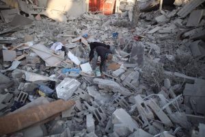 Several people search through the rubble of a building destroyed in an Israeli airstrike