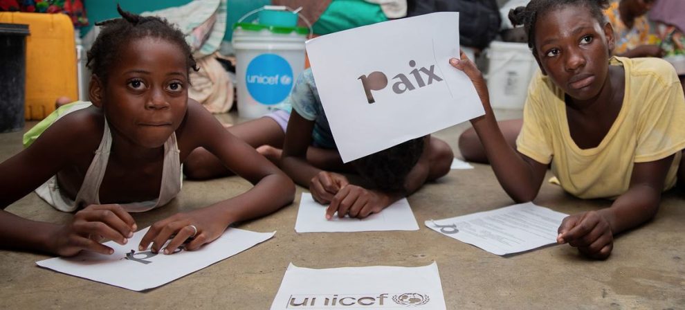 A student from Port-au-Prince holds a sign in French that reads "peace".