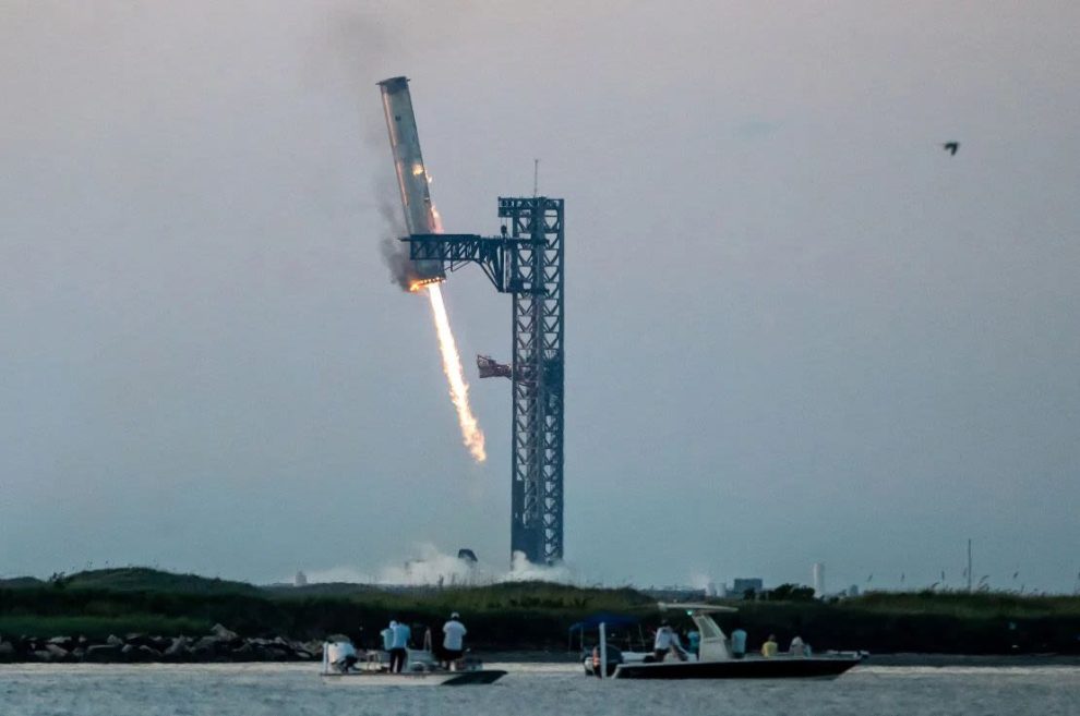 Huge metal clamps grip Starship's Super Heavy rocket booster as it returns to the launch pad at Starbase near Brownsville, Texas, after the Oct. 13 test flight. The maneuver was a first in SpaceX's attempt to make the rocket reusable.